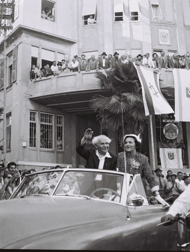 ראש הממשלה דוד בן גוריון ורעייתו פולה חולפים על פני בניין עיריית תל אביב בדרכם הביתה, עם חזרתם מביקור בארה"ב - פין הנס (חיים)