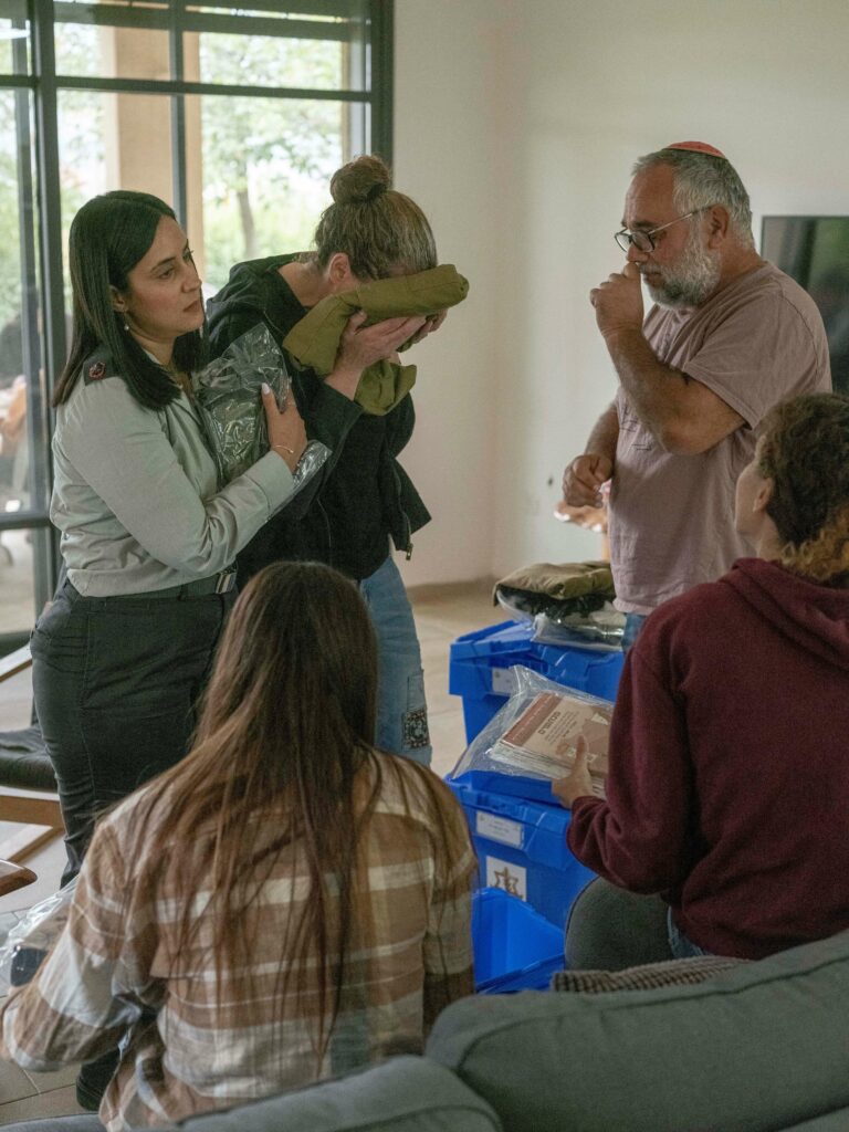חרבות ברזל. הארגזים בבית משפחת אמר. האם גילנית מליטה את פניה במדים של בנה רגב, כשליצידה האב רוני ובנותיהן וקצינת הנפגעים. - חן יובל