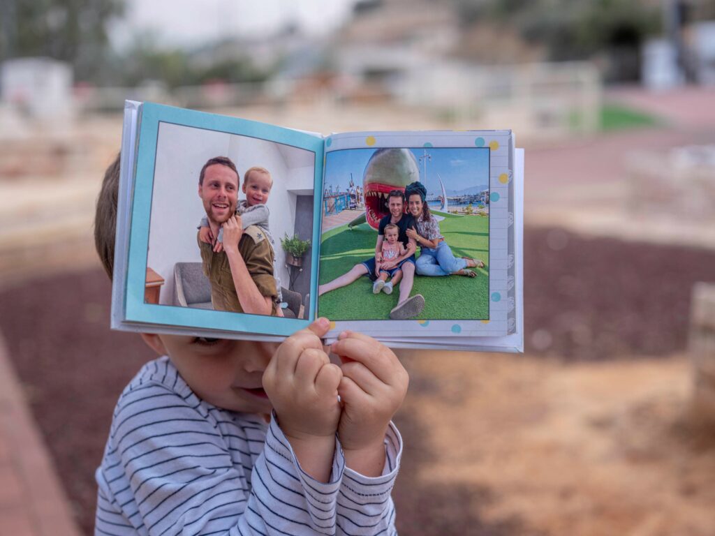 חרבות ברזל. לביא שמיר עם אלבום משפחתו ליד קבר אביו, שנפל בקרב ב7 באוקטובר בקיבוץ רעים - חן יובל