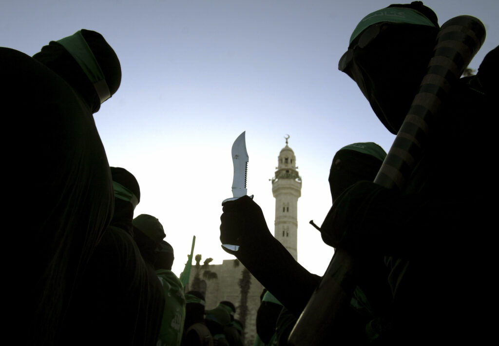 A masked militant of the Palestinian Islamic group Hamas holds a knife while marching during a rally - בלילטי עודד