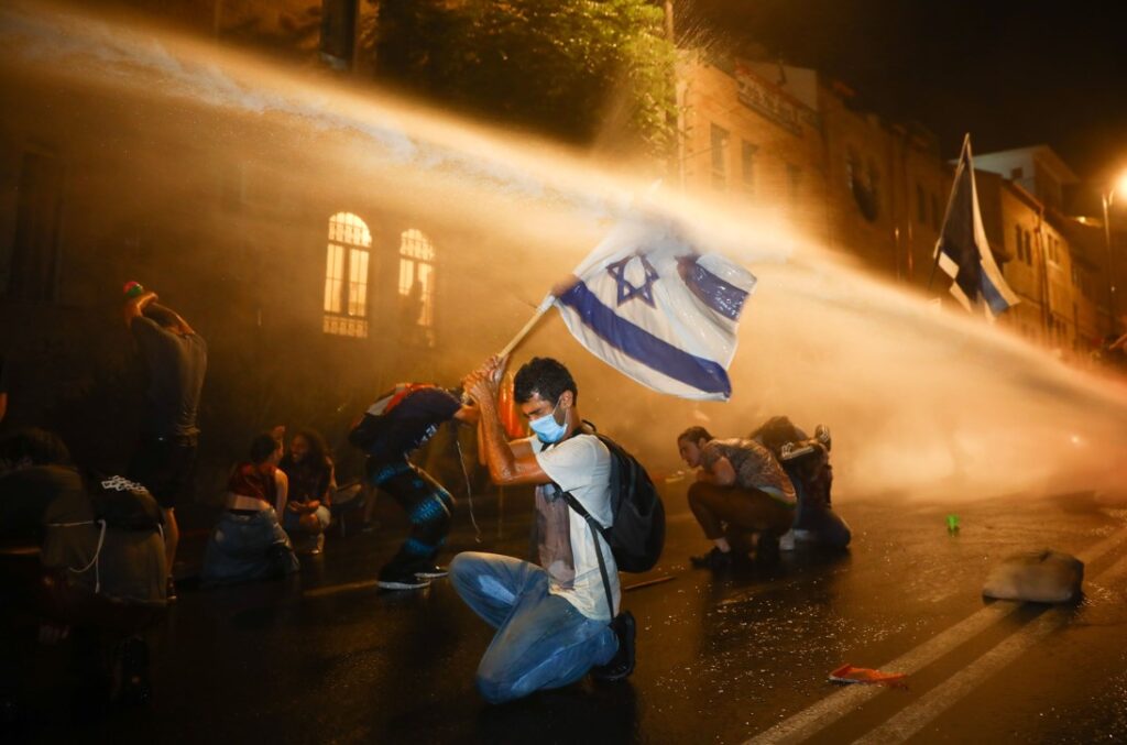 Police use a water cannon to disperse protesters demonstrating against Israeli Prime Minister Benjamin Netanyahu - בלילטי עודד